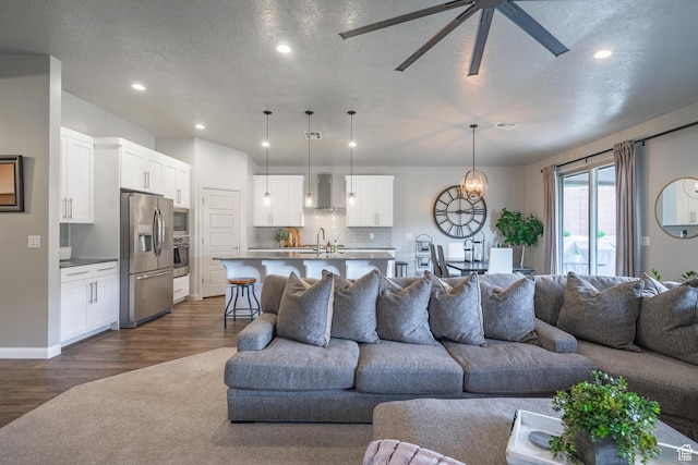 658 N Sage Crest Dr, Washington, UT 84780 - living room featuring dark wood finished floors, recessed lighting, ceiling fan with notable chandelier, and a textured ceiling