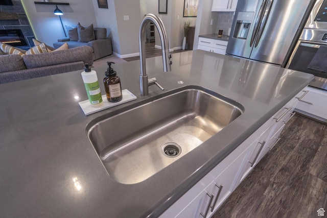 658 N Sage Crest Dr, Washington, UT 84780 - interior details featuring a sink, a glass covered fireplace, oven, dark countertops, and white cabinets