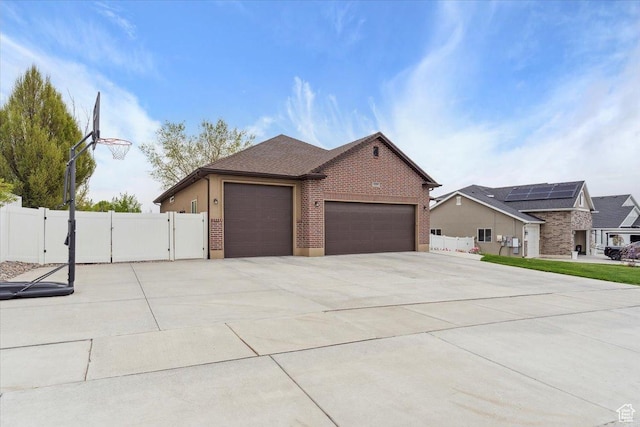 view of side of home with fence, a gate, brick siding, and a garage