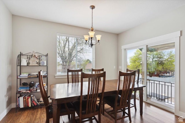 dining room featuring an inviting chandelier, wood finished floors, and baseboards