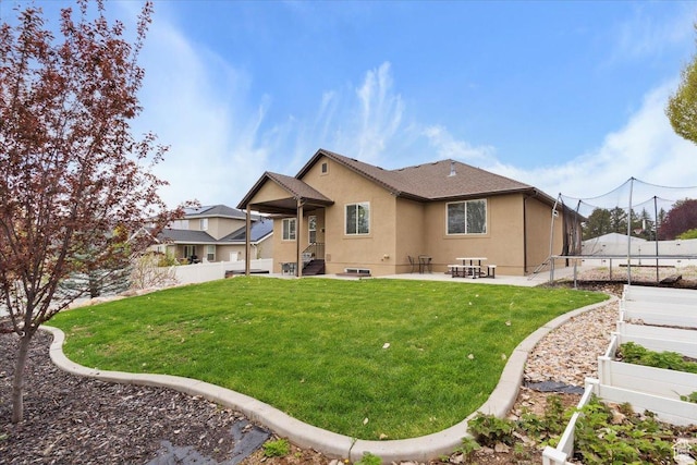 back of house featuring a trampoline, stucco siding, a yard, and a patio area
