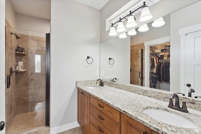 bathroom featuring a spacious closet, a stall shower, double vanity, and a sink
