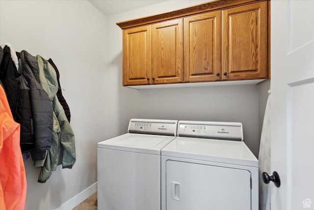 clothes washing area featuring separate washer and dryer, cabinet space, and baseboards