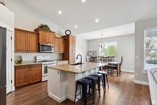 kitchen with stainless steel microwave, brown cabinets, a sink, a breakfast bar, and white gas stove