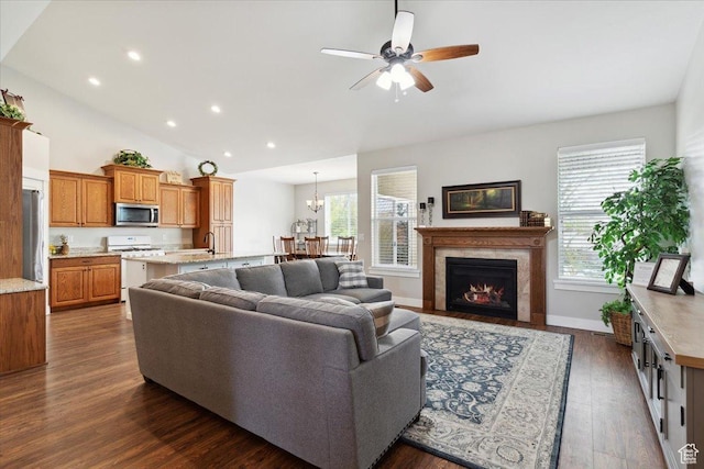 living room with recessed lighting, dark wood-style floors, high vaulted ceiling, a ceiling fan, and a lit fireplace