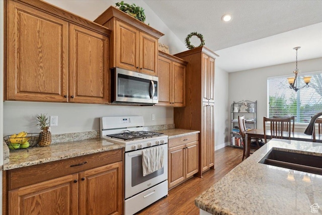 kitchen with stainless steel microwave, a sink, a chandelier, wood finished floors, and white gas stove