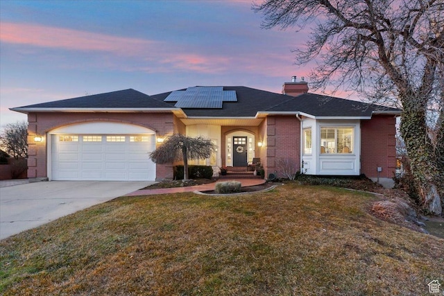 4972 S Boabab Crk, Holladay, UT 84117 - view of front facade featuring a chimney, brick siding, a lawn, concrete driveway, and an attached garage