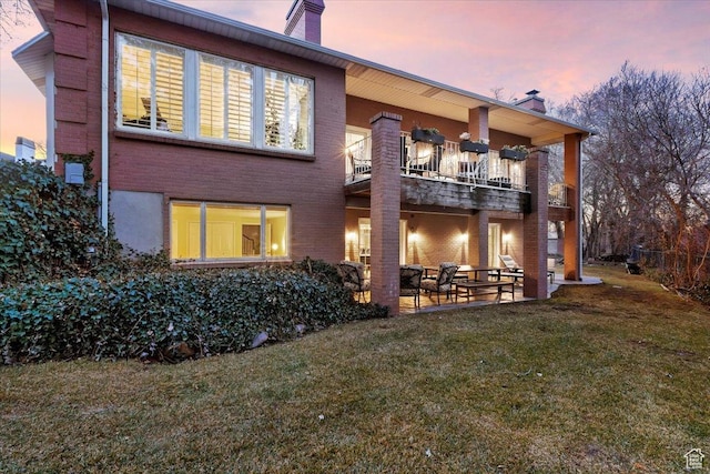 4972 S Boabab Crk, Holladay, UT 84117 - back of house at dusk featuring a chimney, a balcony, a yard, and a patio area