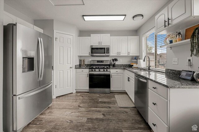 4799 S 3950 W, Roy, UT 84067 - kitchen with appliances with stainless steel finishes, a sink, white cabinetry, a textured ceiling, and dark wood-type flooring