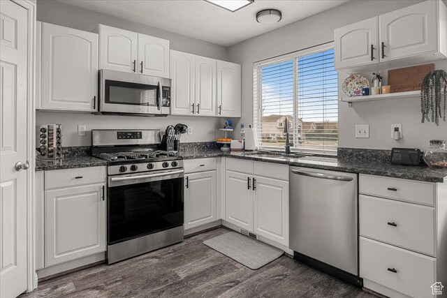 4799 S 3950 W, Roy, UT 84067 - kitchen featuring dark stone counters, stainless steel appliances, white cabinets, a sink, and dark wood-type flooring