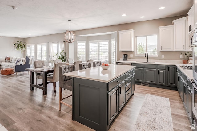 9061 N Clubhouse Ln, Eagle Mountain, UT 84005 - kitchen featuring a sink, a breakfast bar, white cabinetry, gray cabinetry, and open floor plan