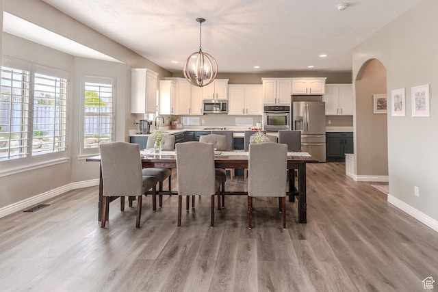 9061 N Clubhouse Ln, Eagle Mountain, UT 84005 - dining area with light wood finished floors, recessed lighting, a notable chandelier, baseboards, and arched walkways