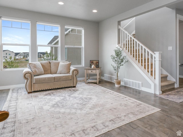 living area featuring wood finished floors, visible vents, and stairs