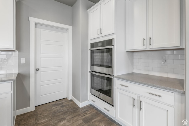 kitchen featuring double oven, baseboards, tasteful backsplash, and dark wood finished floors