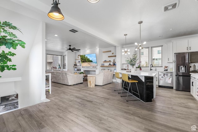kitchen with appliances with stainless steel finishes, a breakfast bar area, white cabinetry, open floor plan, and light countertops