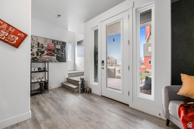 doorway to outside with wood finished floors, stairs, plenty of natural light, and baseboards