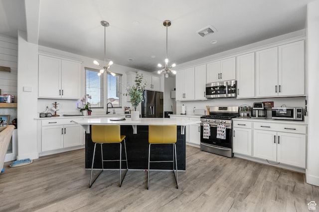 kitchen featuring appliances with stainless steel finishes, a breakfast bar area, light wood-type flooring, and white cabinetry