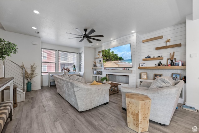 living room featuring ceiling fan, light wood finished floors, baseboards, recessed lighting, and a large fireplace