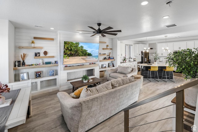 living area with a ceiling fan, wood finished floors, a chandelier, and recessed lighting