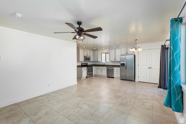 kitchen featuring light tile patterned floors, dark countertops, stainless steel appliances, baseboards, and ceiling fan with notable chandelier