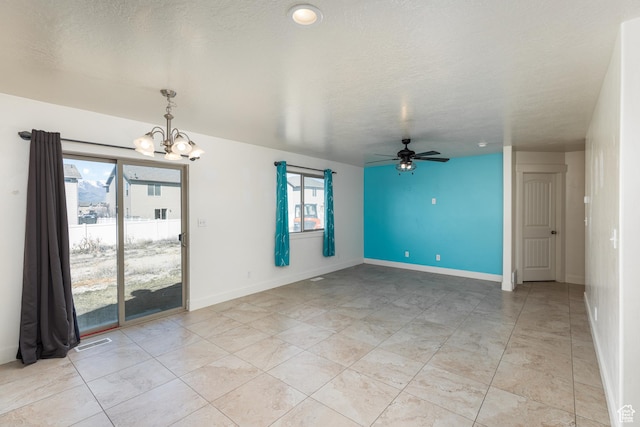 spare room featuring baseboards, visible vents, ceiling fan with notable chandelier, and a textured ceiling