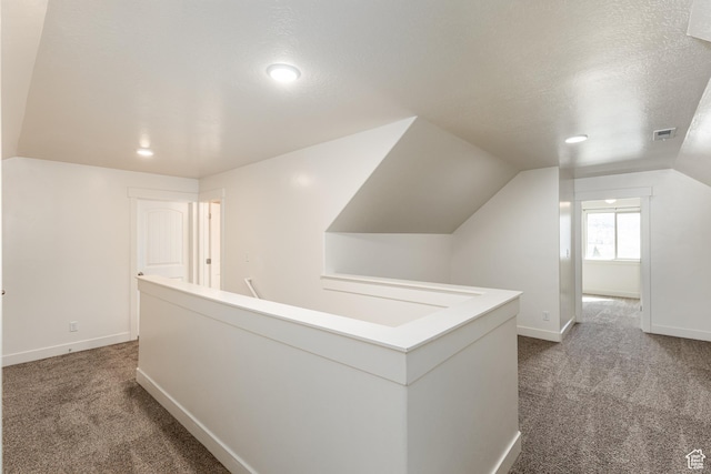 hall featuring recessed lighting, visible vents, dark carpet, and lofted ceiling