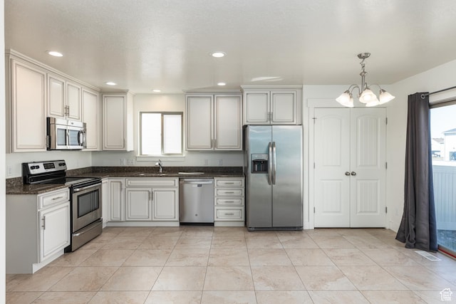 kitchen featuring pendant lighting, a sink, appliances with stainless steel finishes, a chandelier, and visible vents