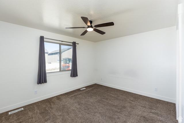unfurnished room featuring baseboards, visible vents, dark colored carpet, and a ceiling fan