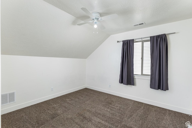 bonus room with dark colored carpet, visible vents, a ceiling fan, and vaulted ceiling