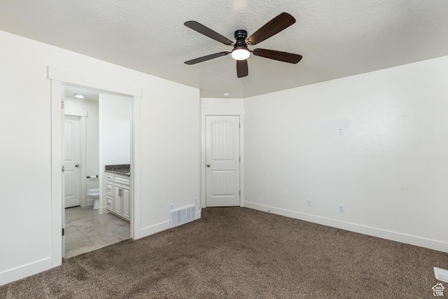 unfurnished bedroom with baseboards, visible vents, ensuite bath, and carpet floors