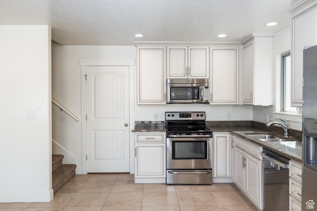 kitchen featuring recessed lighting, dark stone counters, appliances with stainless steel finishes, a sink, and light tile patterned flooring