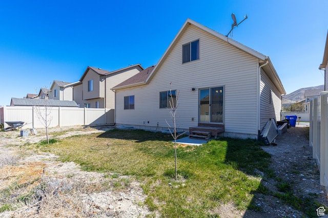 back of house with fence, a lawn, and entry steps