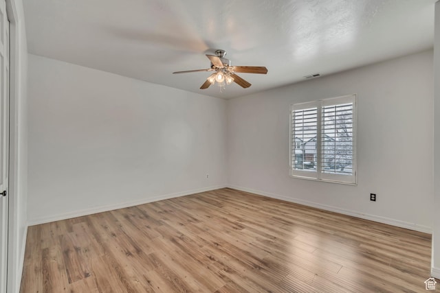 spare room with baseboards, a ceiling fan, and light wood finished floors