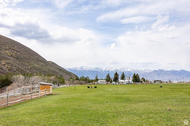 view of yard featuring a rural view, fence, and a mountain view