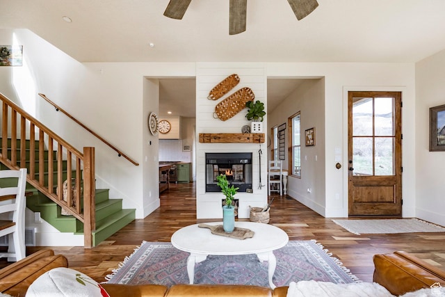 living area featuring baseboards, ceiling fan, wood finished floors, and stairway