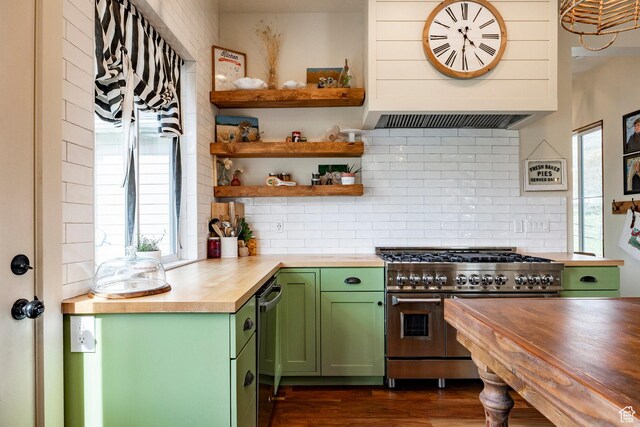 kitchen featuring wooden counters, green cabinets, backsplash, exhaust hood, and double oven range