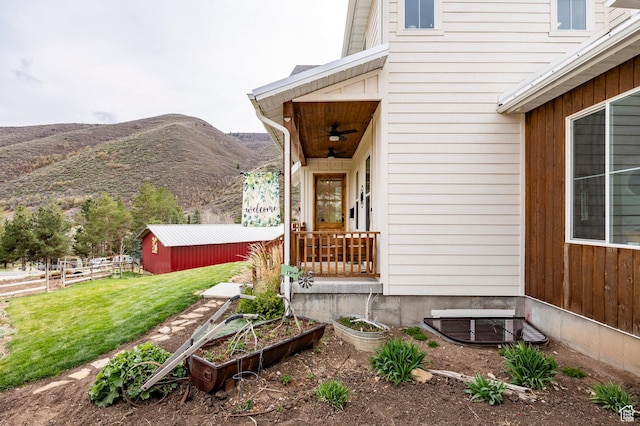 entrance to property with a lawn, fence, a ceiling fan, and a mountain view