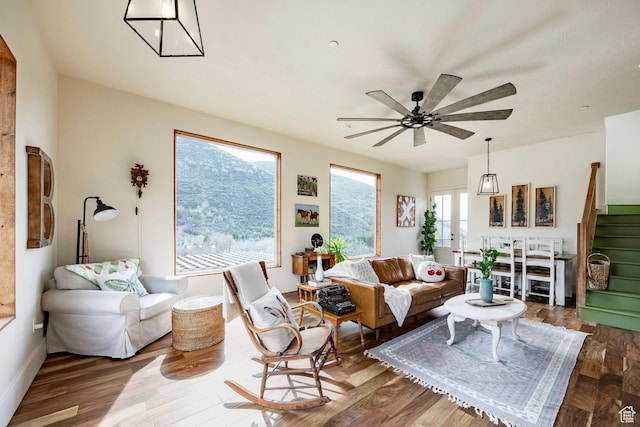 living area with baseboards, stairs, ceiling fan, and wood finished floors