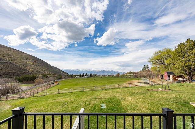 view of yard with a rural view, fence, an outbuilding, and a mountain view