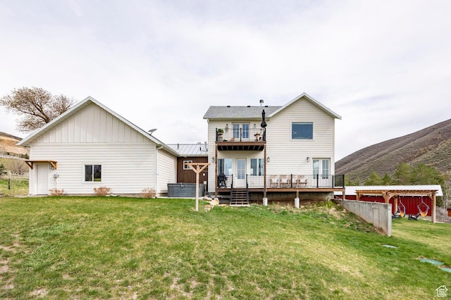 back of house featuring board and batten siding, a lawn, a deck with mountain view, and a balcony