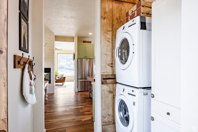 laundry room featuring stacked washer and clothes dryer and wood finished floors