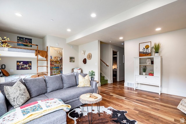 living area featuring recessed lighting, baseboards, wood finished floors, and stairway