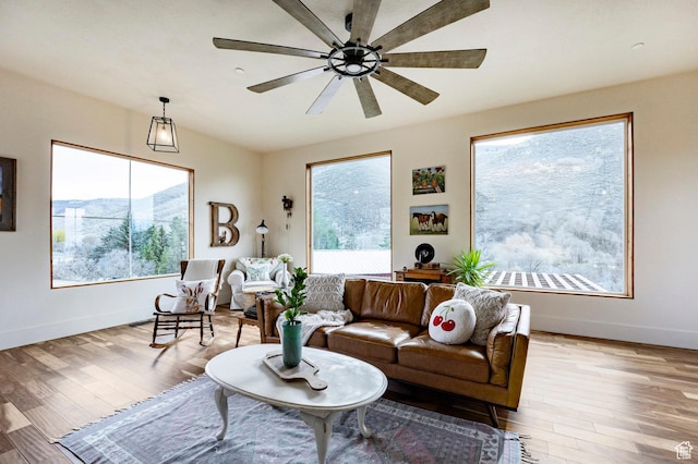 living room featuring baseboards, light wood finished floors, and a wealth of natural light