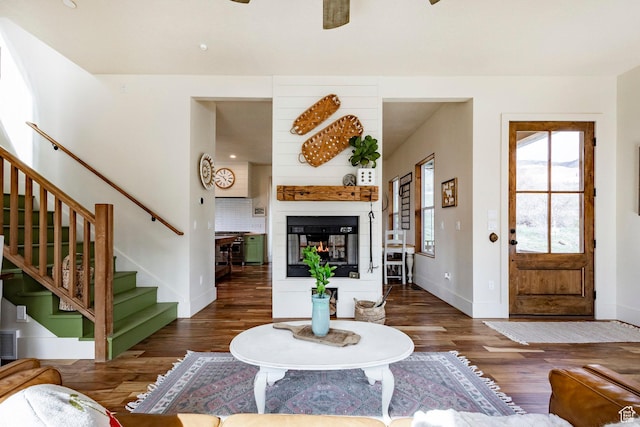 living area with baseboards, ceiling fan, wood finished floors, and stairway