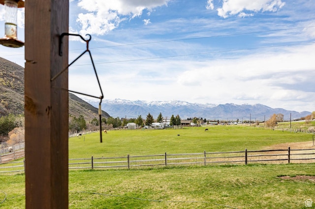 view of yard featuring a rural view, fence, and a mountain view