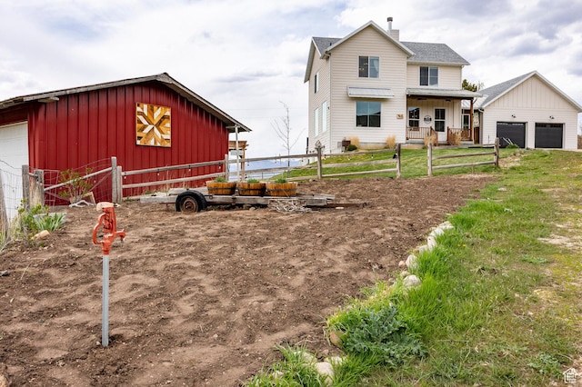 view of front of house with a garage, board and batten siding, fence, and an outbuilding