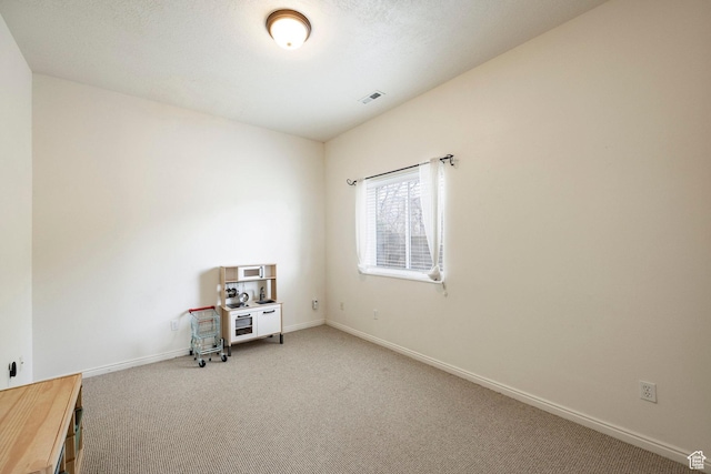 miscellaneous room with visible vents, light colored carpet, and baseboards