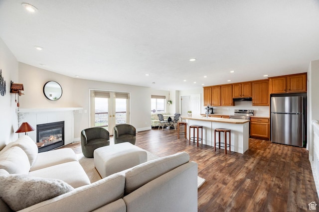 living area featuring dark wood finished floors, recessed lighting, a tile fireplace, and french doors