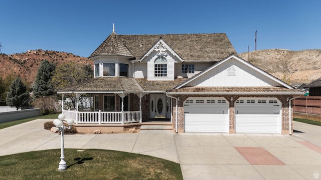 889 Upland Dr, Richfield, UT 84701 - victorian house featuring a porch, brick siding, driveway, a mountain view, and an attached garage