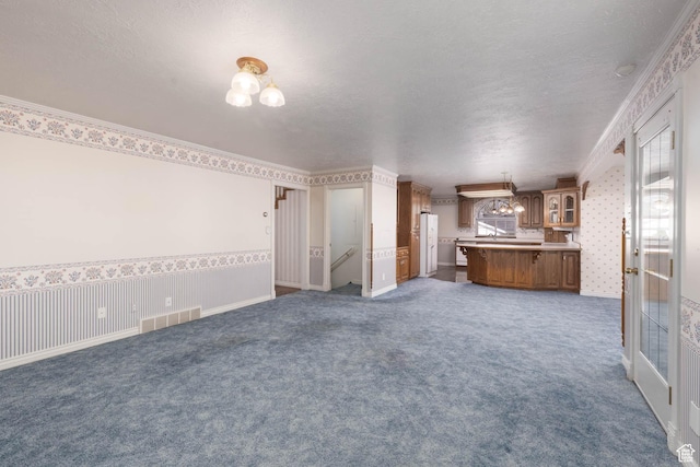 889 Upland Dr, Richfield, UT 84701 - unfurnished living room featuring wallpapered walls, a textured ceiling, and carpet floors